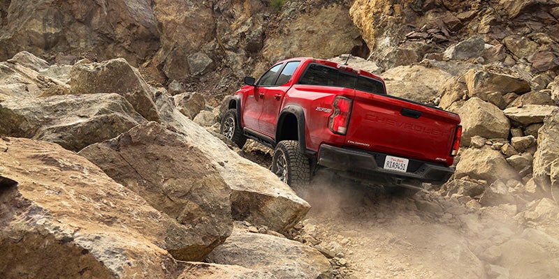 Image of red 4x4 Chevrolet truck driving on the rocks and mountains