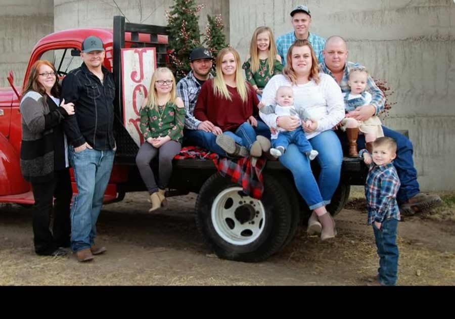 Image of Mindy Bringard and his family setting around old classic red truck